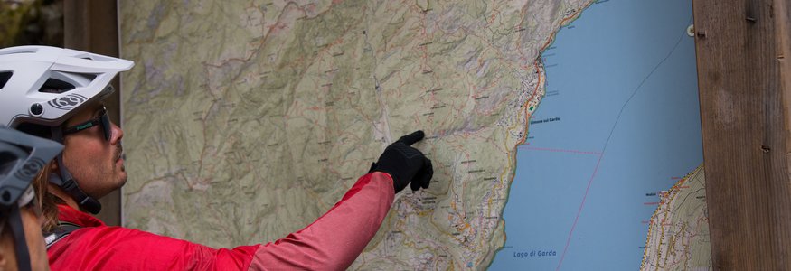 Personen mit Fahrradhelm betrachten eine Wanderkarte am Gardasee
