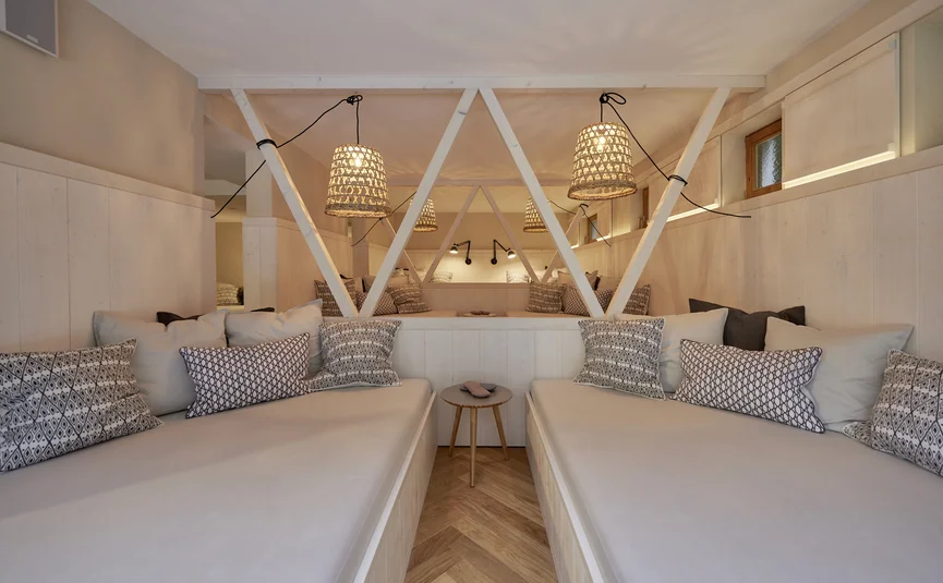 Gezellige woonkamer met twee banken, kussens en hanglampen in een lichte ruimte