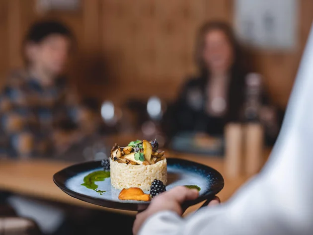 Kok serveert verfijnd gerecht op zwart bord aan gasten