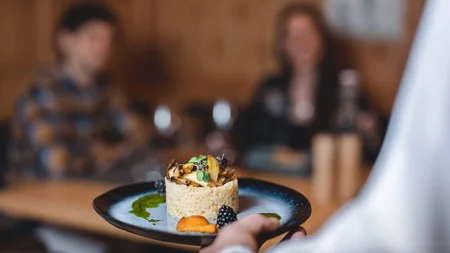 Kok serveert verfijnd gerecht op zwart bord aan gasten