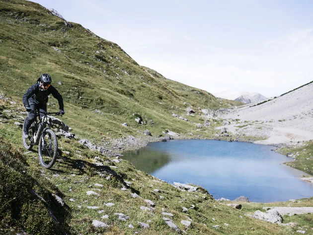 Mountainbiker fährt auf einem Pfad neben einem Bergsee in den Alpen