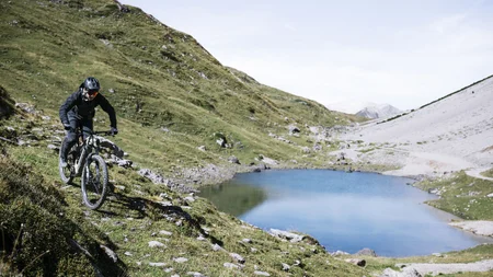 Mountainbiker fährt auf einem Pfad neben einem Bergsee in den Alpen