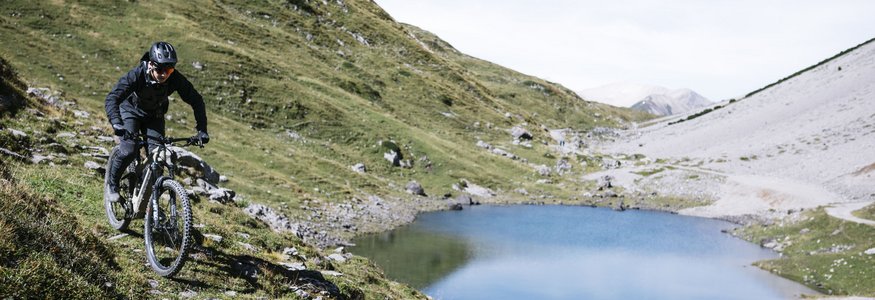 Paradise Lodge ****S © Martina Wunderle Mountainbiker fährt auf einem Pfad neben einem Bergsee in den Alpen