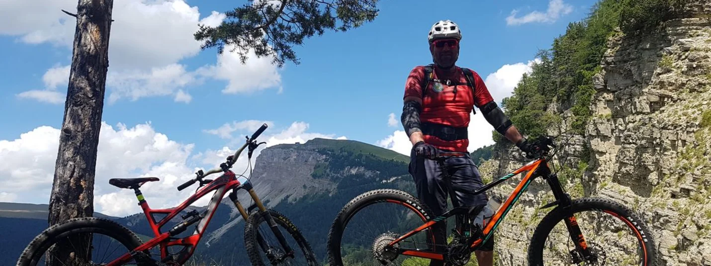 TOUR VAL GARDENA - VALLUNGA - S. GIACOMO © Hotel Digon St. Ulrich Mountainbiker met twee fietsen op rotsachtig bergpad met klif en lucht