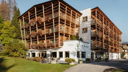 Hotel Melodia del Bosco met houten balkons en bloemen in groene omgeving