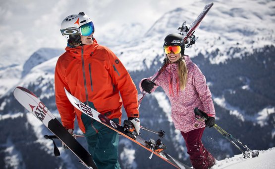 Twee skiërs met uitrusting in besneeuwde bergen