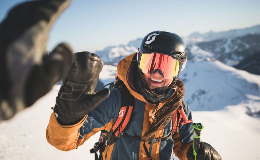 Skier wearing helmet and goggles giving high five in snowy mountain