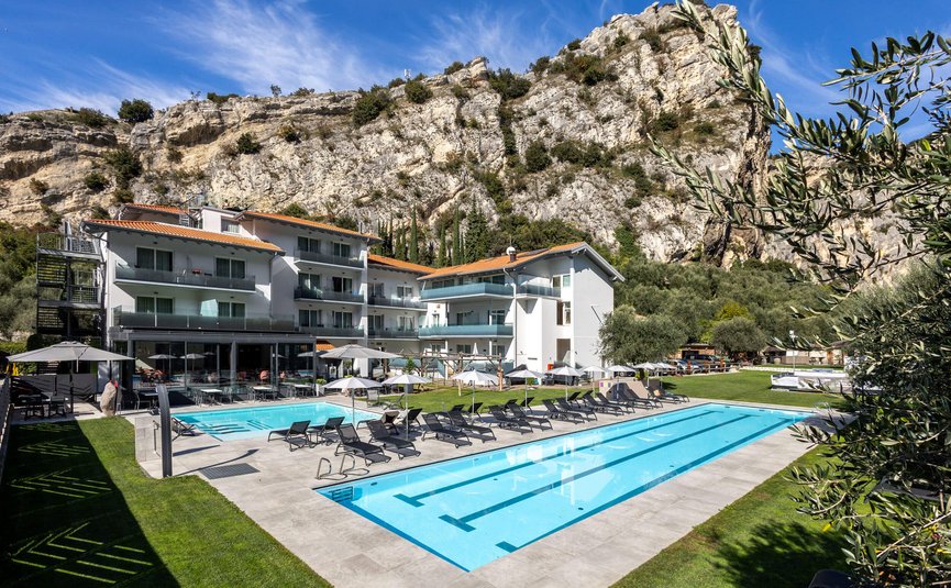 AktivHotel SantaLucia Gardasee **** © Fabio Staropoli Hotel mit Außenpool und Liegestühlen vor Felsen unter blauem Himmel
