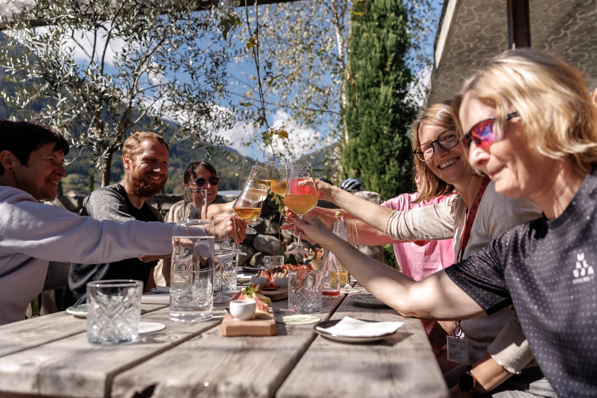 Das war die bike festa Südtirol in Brixen © Brixen Tourismus Eine Gruppe stößt an einem Holztisch im Freien mit Gläsern an