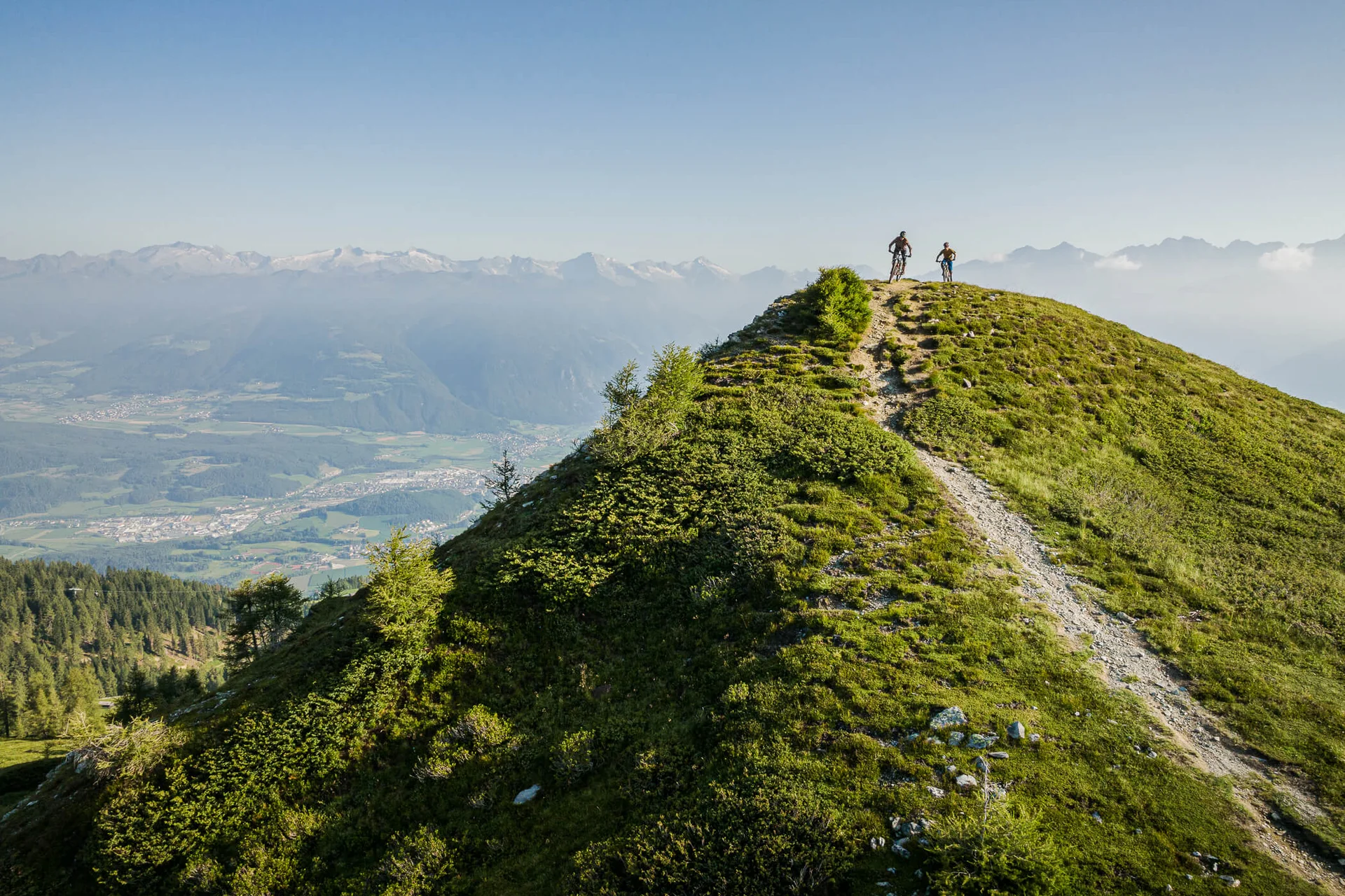 Zwei Radfahrer auf einem bergigen Wanderweg mit Tal- und Bergsicht