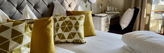 Ab auf die Piste im Jänner! Gemütliches Bett mit gelben und weißen Kissen in einem modernen Hotelzimmer