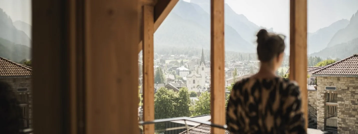 Frau schaut durch Fenster auf Stadt mit Bergen im Hintergrund