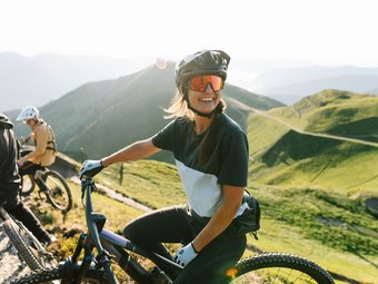 Woman with mountain bike and helmet on sunny mountain trail