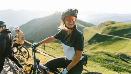 Vrouw met mountainbike en helm op zonnig bergpad
