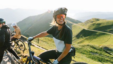 Woman with mountain bike and helmet on sunny mountain trail