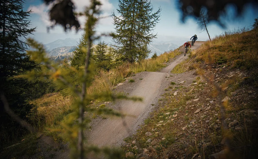 Two mountain bikers riding down a winding mountain trail