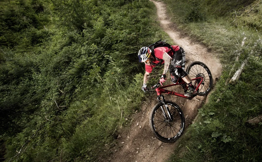 Mountainbiker mit Helm auf Waldpfad fährt Kurve