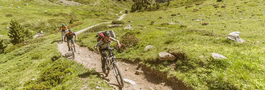 Mountain biking in Lombardy © Hansi Heckmair Three mountain bikers riding on narrow trail in green mountainous landscape