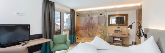 Lifesporthotel Hechenmoos *** © Multivisual Art Modernes Hotelzimmer mit Doppelbett, TV, Stühlen und Glasdusche