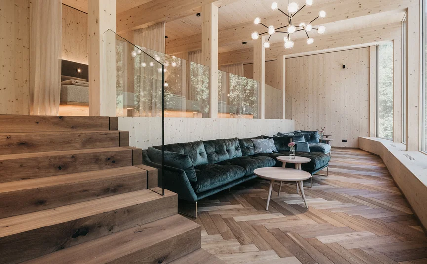 Helles Wohnzimmer mit Holzboden, grüner Couch und moderner Treppe aus Holz