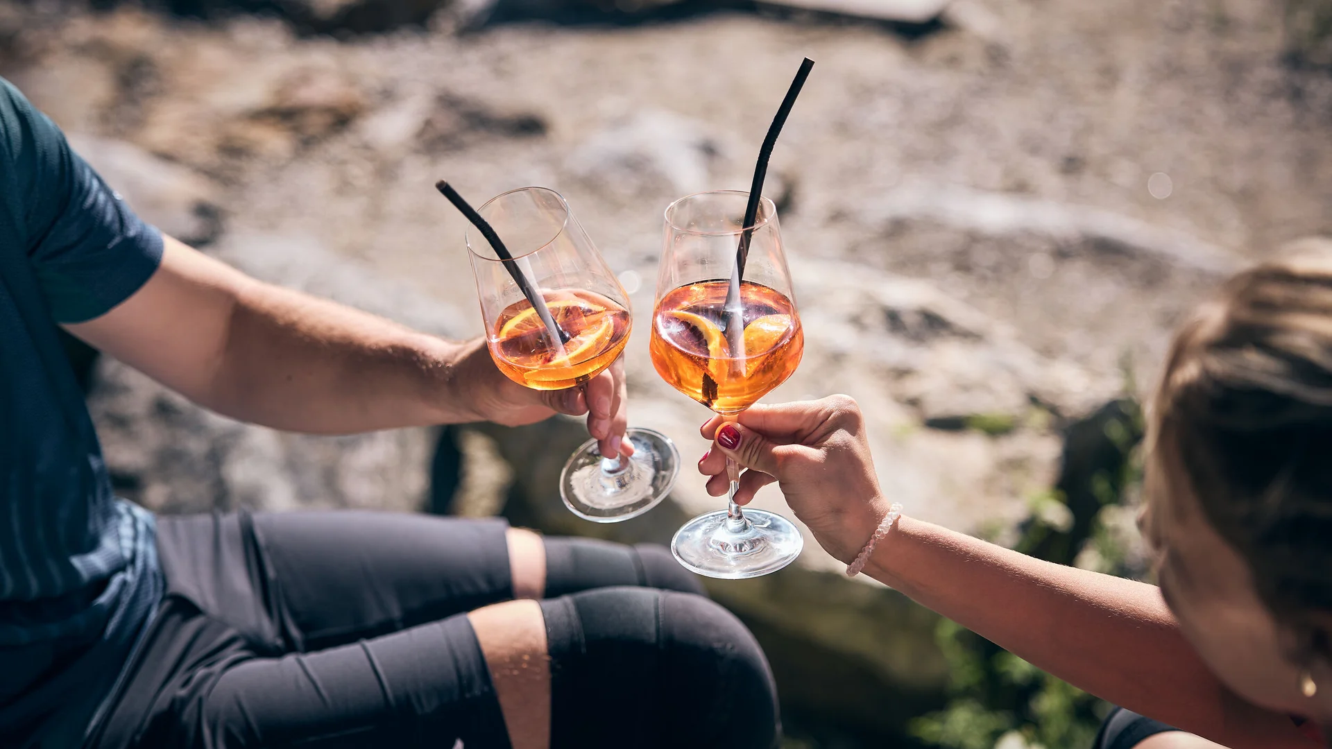 Zwei Personen stoßen mit Aperol Spritz Gläsern im Freien an