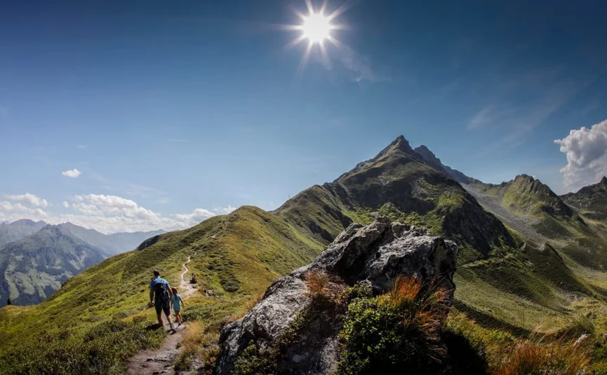 Wanderer auf einem Bergpfad bei sonnigem Himmel in den Alpen