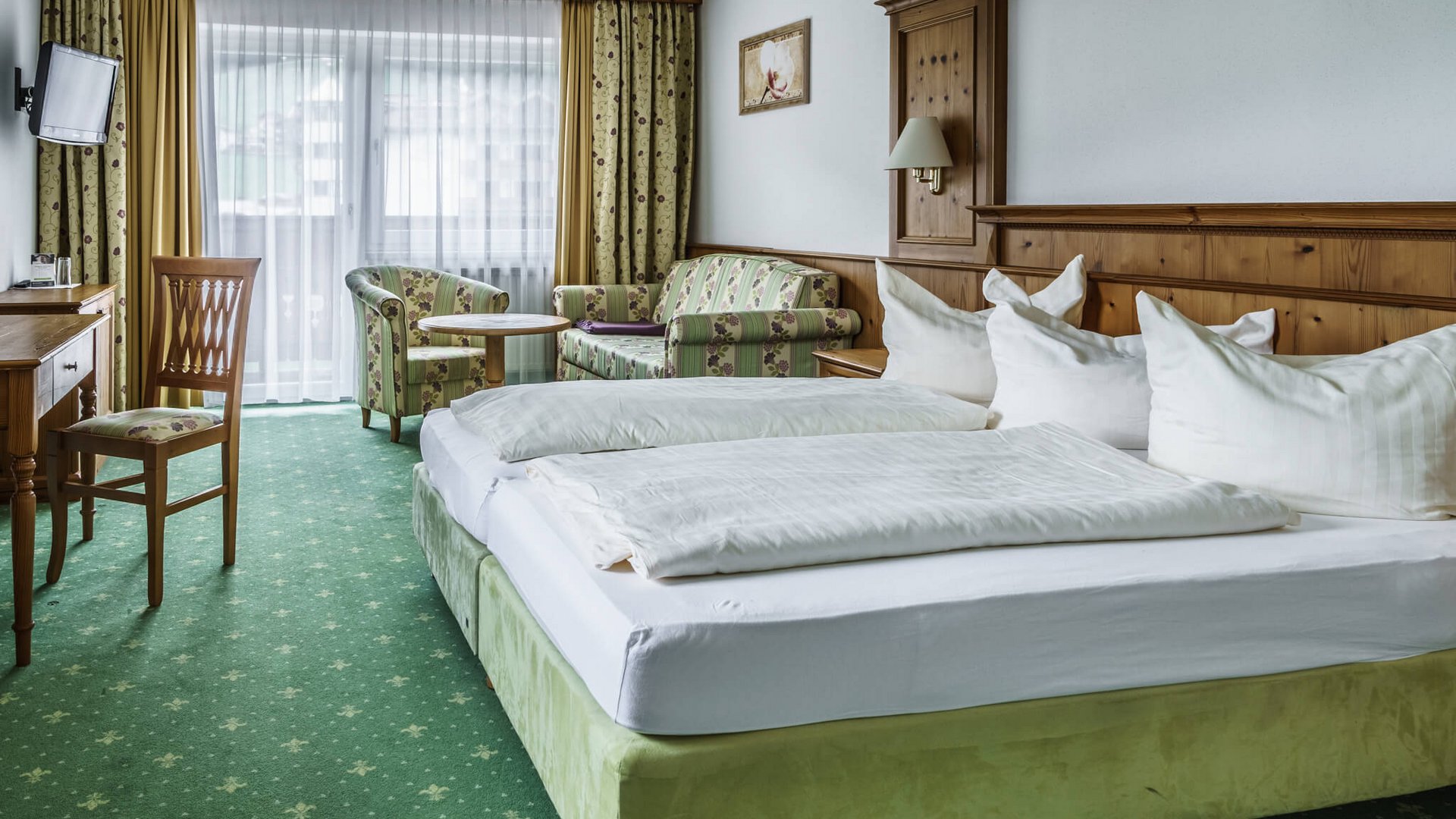 Gemütliches Hotelzimmer mit grünem Teppich und Holzmöbeln