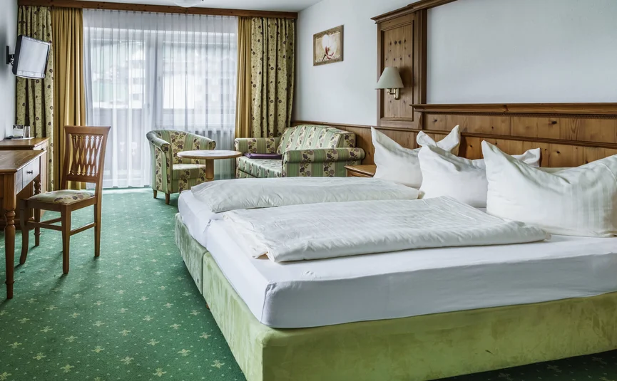 Gezellige hotelkamer met groen tapijt en houten meubels