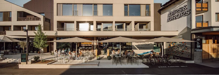 Modernes Gebäude mit Außenterrasse und Sitzplätzen bei Sonnenschein