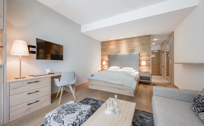 Modernes Hotelzimmer mit Bett, Fernseher, Sitzbereich und Schreibtisch