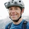 Mann mit Fahrradhelm und Rucksack vor Bergpanorama