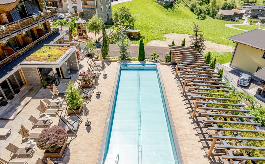 Hotel Weisses Lamm **** © Stephanie Maria Lohmann Leerer Poolbereich mit Liegestühlen in einem Bergresort an sonnigem Tag