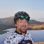 Radfahrer vor Bergsee und Gipfel im Sonnenlicht