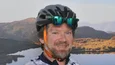 Radfahrer vor Bergsee und Gipfel im Sonnenlicht
