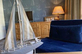 Modellsegelboot neben blauem Sofa in maritim dekoriertem Zimmer