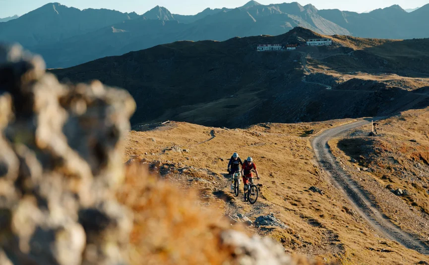 Twee mountainbikers rijden op een zonnig bergpad