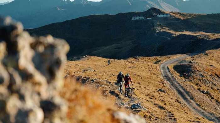 Zwei Mountainbiker fahren auf einem Bergweg bei Sonnenlicht