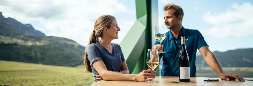 Zwei Personen trinken Weißwein bei einer Weinprobe mit Bergblick