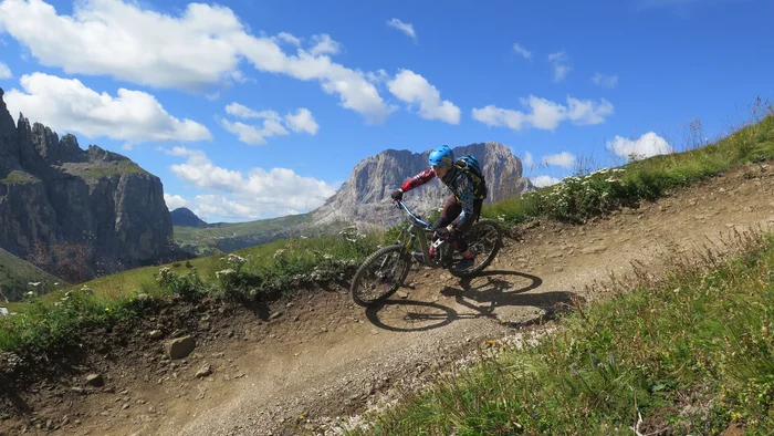 Mountainbiker fährt auf einem Bergpfad mit Alpen im Hintergrund