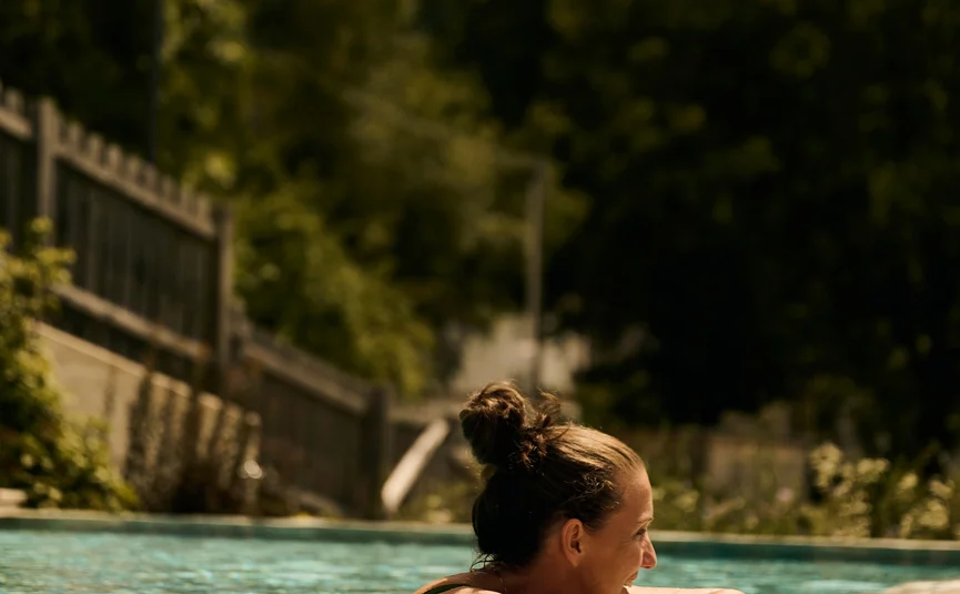 HIRBEN Naturlaub **** © David Rasche Woman relaxing in outdoor pool with green trees in background