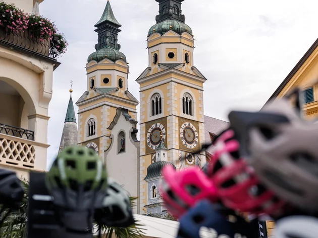 Das war die bike festa Südtirol in Brixen © Brixen Tourismus - Brixen Dom bike festa Südtirol 2026 Kirche mit zwei Uhrturmspitzen, im Vordergrund unscharfe Fahrräder und Helme