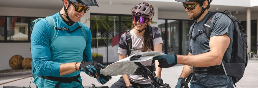 Drei Radfahrer planen ihre Route mit Karte vor dem Hohe Salve Sportresort