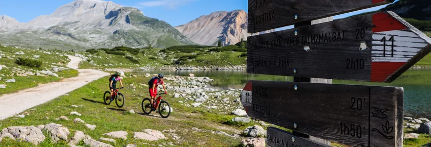 Bikeurlaub per Bahn © Norman Bielig Zwei Radfahrer auf Bergweg bei Wegweiser in den Dolomiten