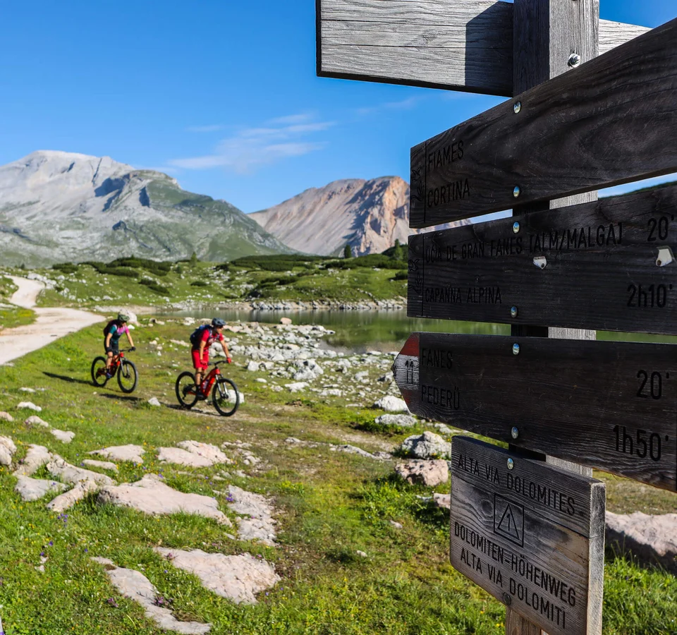 Zwei Radfahrer auf Bergweg bei Wegweiser in den Dolomiten