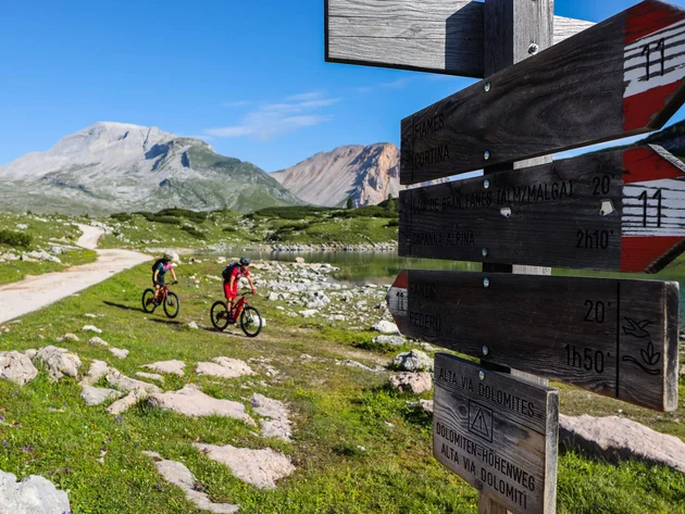 Ein Herbst-Wochenende in San Vigilio © Norman Bielig Zwei Radfahrer auf Bergweg bei Wegweiser in den Dolomiten