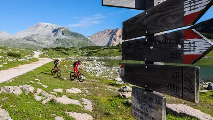 Zwei Radfahrer auf Bergweg bei Wegweiser in den Dolomiten