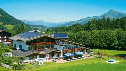 Alpenhaus mit Solarpanels und Terrasse in grüner Berglandschaft