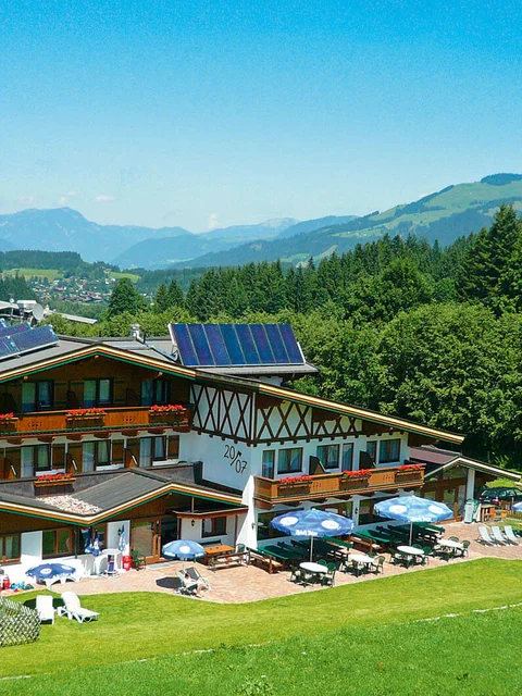 Alpenhaus mit Solarpanels und Terrasse in grüner Berglandschaft