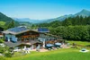 Alpenhaus mit Solarpanels und Terrasse in grüner Berglandschaft