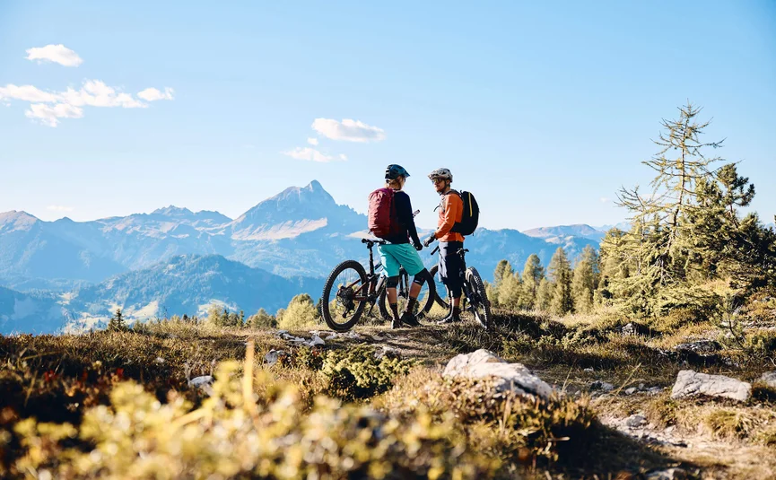 Zwei Mountainbiker stehen mit ihren Fahrrädern in den Bergen bei klarem Himmel